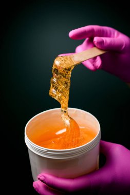 Saç kesme prosedürü için şeker macunu ve ince ahşap bir spatula ile pembe kauçuk eldiven ustaları