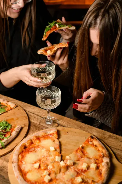 Girls eat pizza. Pieces of juicy aromatic pizza with mozzarella on a set table for a holiday