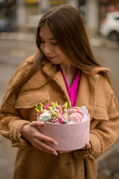 Kahverengi Ceketli Gülümseyen Güzel Kadın Elinde Çiçek Badem Kurabiyeleriyle Hediye — Stok fotoğraf