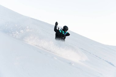 Siyah-mavi kayak takımlı tek kollu erkek kayakçı yamaçtan aşağı iniyor.