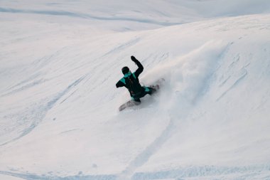 Snowboard yapan tek kollu erkek snowboardcu başka bir manevranın üstesinden geliyor böylece düşecek gibi görünüyor.