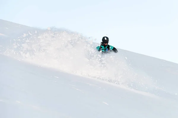 青いスーツの片腕の男性スキーヤーは雪の斜面を下り 雪は異なる方向に飛ぶ — ストック写真