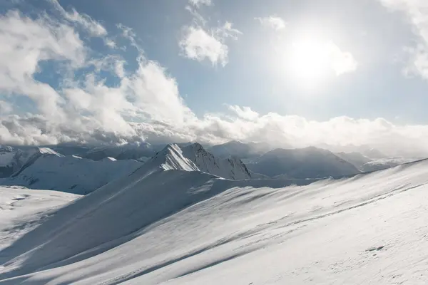 雪山の山頂は 白い雲と明るい太陽 サイドビューの青空の背景から見えます — ストック写真