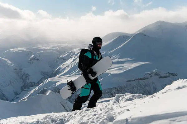 Snowboardcu Kar Kaykayını Elinde Tutarak Puslu Bulutlarla Kaplı Dağ Zirvelerine — Stok fotoğraf
