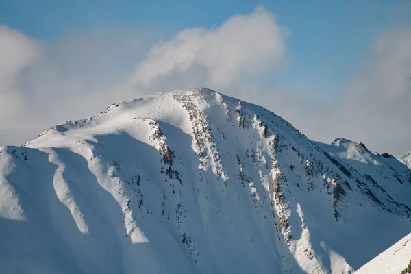 雪に覆われた山頂のクローズアップ写真ですが 岩の黒いアウトクロップは部分的に見えます — ストック写真