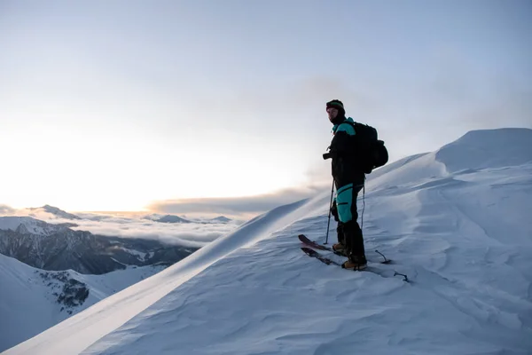 滑雪者爬上山坡 背靠着笼罩在雾中的高山 另一个滑雪者几乎站在山顶 — 图库照片