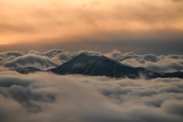 山の頂上は クリムゾン空と日の出の背景に対して霧を通してほとんど見えません — ストック写真