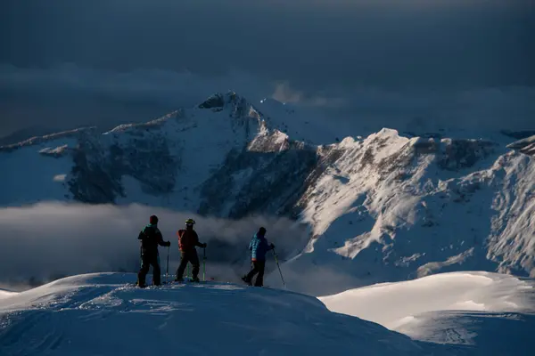 3명의 선수가 눈으로 산봉우리에 안개가 가득한 절벽에 분리된 산봉우리를 봅니다 — 스톡 사진