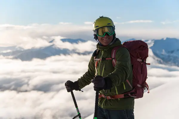 霧の雲の背景に対する最高峰の上のスキーの上に立っている幸せなフリーダーのクローズアップ写真 — ストック写真