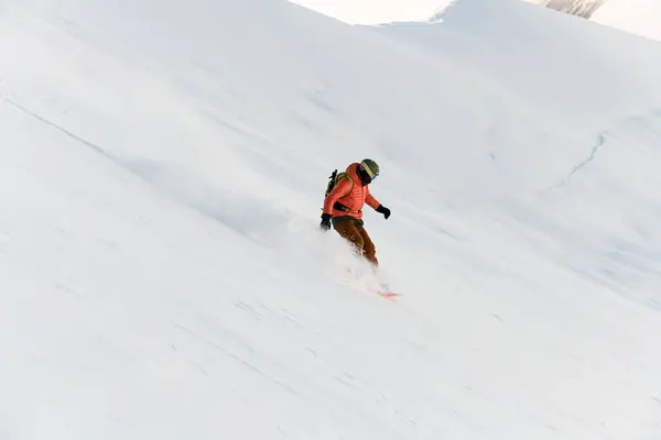 スノーボードの急な雪の斜面と雪がさまざまな方向に飛んでいる赤いジャケットのスノーボーダーのトップビュー — ストック写真