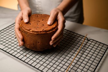 Lezzetli kek ızgaranın üzerinde duruyor, krema, kuru üzüm, meyve, şekerleme, kurabiye, kurabiye ile süslenmeye hazır.
