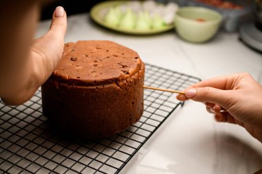 İştah açıcı turta ızgarada duruyor, krema, kuru üzüm, şekerli meyveler, kurabiyeler, kurabiyeler ile süslenmeye hazır.