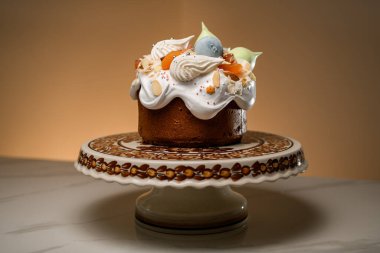 Beyaz kremalı pasta, mavi ve pembe makaronlar, şekerli meyveler ve badem dolgulu ve seramik tezgahta narin krema.