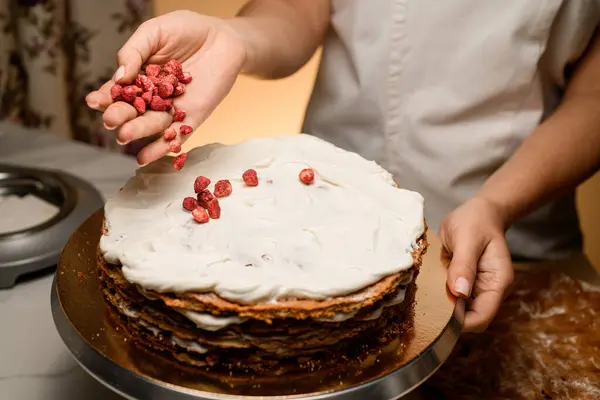 糕点师在生日蛋糕上涂上粉红草莓 在蛋糕架上涂上蓬松的白色厚奶油 — 图库照片