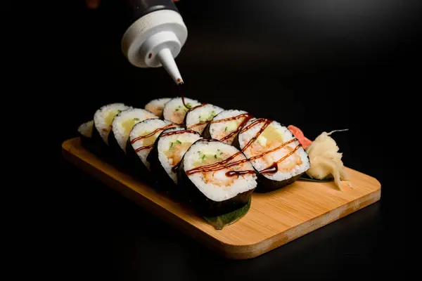 Sushi Rolky Zázvorem Dřevěné Desce Máčené Omáčkou Izolované Černém Pozadí — Stock fotografie
