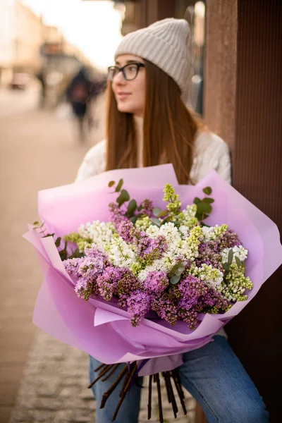 Wanita Cantik Berkacamata Memegang Karangan Bunga Dengan Pembungkus Ungu Melihat — Stok Foto