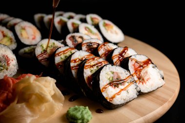 Ön plana odaklan, salatalık, karides eti ve unagi sosu şişeden, wasabi ve zencefilli ahşap tahtaya.