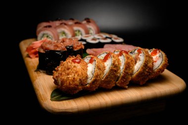 Kızarmış suşi rulolarının ön planına odaklan, ketçap damlaları diğer ruloların bulanık arka planında olsun.