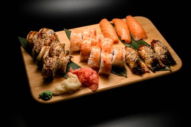 Suşi dilimli ahşap tahta: iki çeşit nigiri, karidesli Philadelphia ve ton balıklı kızartma