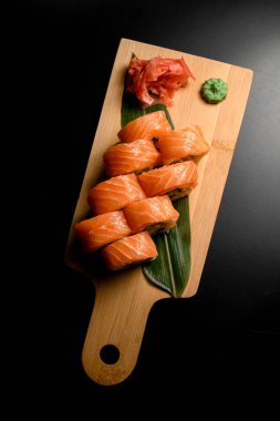 Philadelphia 'nın en iyi somon suşisi manzarası. Krem peynirli. Tahta tahtada, siyah masa arkasında.