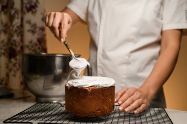 Uzman eller Paskalya pastasını süsler, kremalı krema katmanı ekler.