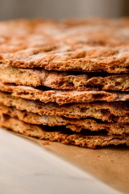 Kesilmiş yuvarlak ballı pastalar parşömen üzerinde kremasız bir şekilde birbirlerinin üzerine uzanırlar.
