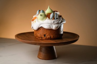 Güzel dekore edilmiş paskalya pastası, badem kurabiyesi ve diğer süslemelerle tahta bir ayakta duruyor.