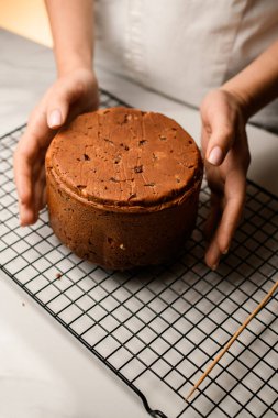Baker, Paskalya pastasını elinde tutuyor. Pasta mutfak masasının üzerinde duruyor.