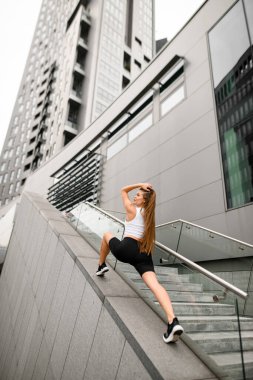 Merdiven, güzelliğini ve gücünü sergileyen atletik bir kızın kendine güvenen ve zarif duruşunun zeminine dönüşür..