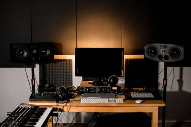 Kayıt stüdyo masasında bir monitör ve müzik kaydetmek için gerekli tüm ekipmanlar, hoparlör sistemi, kulaklıklar, bir Macbook.