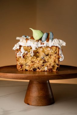 Lezzetli paskalya pastası bej arka planda dekoratif bir tezgahın bir bölümünde krema ve badem kurabiyesi ile süslenmiş.