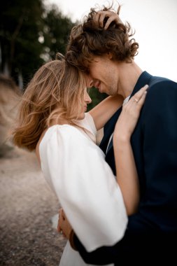 Karı koca birbirine sıkıca sarılıyor ve arka planda birbirine dokunuyor. Yakın plan, yan görüş.