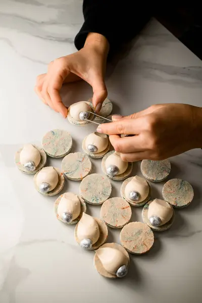 Bovenaanzicht Van Banketbakkers Vrouwelijke Handen Versieren Laatste Witte Macaron Met Rechtenvrije Stockfoto's