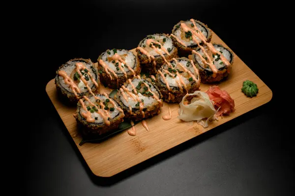 生姜とホットワサビがついた大きな木製板に白米と魚介類がついた天ぷら粉の寿司で揚げる ロイヤリティフリーのストック画像