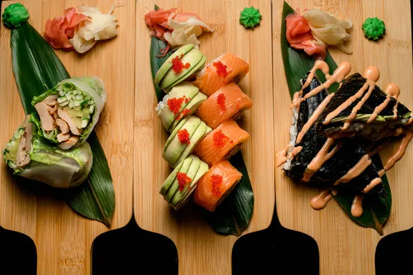 Three Sets Rolls Sushi Three Wooden Boards Long Green Leafs Royalty Free Stock Photos