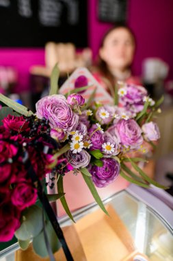 Narin beyaz, leylak güller, papatyalar ve bulanık bir arka planda oturan bir kız.