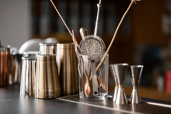 Stock image On the bar there are various dishes and accessories of the bartender for preparing cocktails, a glass, a sieve, jiggers, shakers on a blurred background