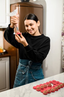 Siyah gömlekli, siyah saçlı, profesyonel bir aşçı. Siyah ve mavi kotlu. Mutfakta kremalı makarna hazırlıyor.