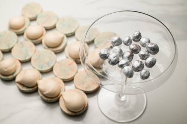 Kurabiyeler için gümüş desenli cam kase ve beyaz mermer bir masada kremalı badem kurabiyesi.