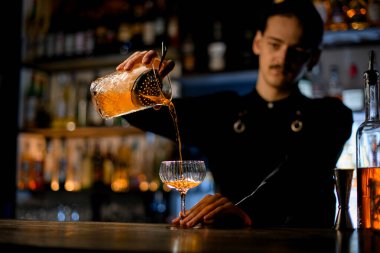 Sıvı sanatının mükemmel kokteylinin karıştırıcı bardaktan, bekleyen kaba nazikçe döküldüğü an..