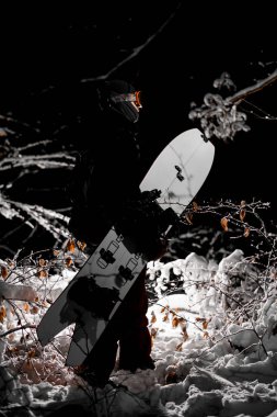 Siyah spor kıyafetleri ve koruyucu gözlük takmış kar üzerinde duran erkek snowboardcuların yan görüntüsü. Kesilmiş atış. Geri yüklenmiş arkaplan.