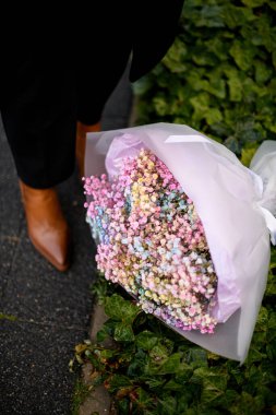 Büyük bir buket çok renkli çingene çiçeği çimenlerin üzerinde uzanıyor. Kahverengi ayakkabılı kadın bacakları var.