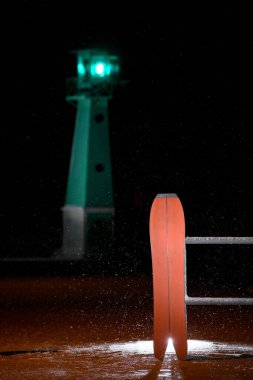 Red splitboard is standing, leaning against a fence, on the sand against a background of a glowing pendulum in total darkness, illuminated from behind by additional light clipart