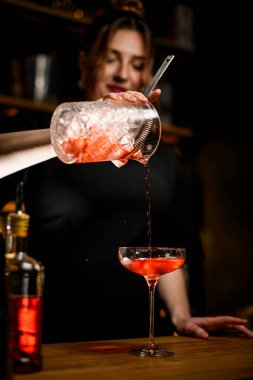 Tatlı bayan barmen, karıştırma bardağından bir bardak dolusu soğuk kahverengi kokteyli süzgeçten geçirirken bitirmiş.