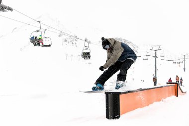 Kayda değer bir beceri sergileyen snowboardcu heyecan verici numaralar yapıyor ve zorlu duvar sürüşünün dengesini koruyor..