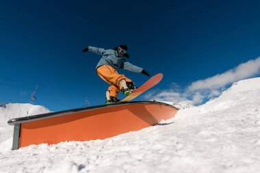 İnceliğini gösteren snowboardcu, karlı yamaçta ustaca hazırlanmış hilelerle dengeyi birleştirir..