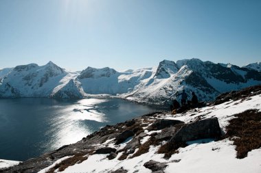 Üç kayakçıdan oluşan bir grup dağın tepesinde durdu. Güneşin yansıttığı güzel dağ manzarasına ve nehre hayran kaldılar.