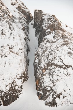 İki kayakçı zaten kayaların arasında oluşan dik dağ inişinin ortasına ulaşmıştı, bu yüzden çok fazla kar vardı.