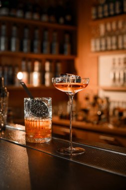 Bulanık bir arka planda barın üstünde buzlu kokteyl ile doldurulmuş bardakla saplı bardağı karıştırmak.