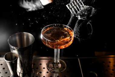 Top view of male bartender hands crushing an ice cube with an ice pick, holding it in a towel directly above a glass with a drink clipart